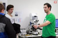 doktorand Haršáni študentom ukazuje napovlakovaný vrták, v pozadí laserový konfokálny mikroskop