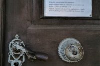 Kostol Povýšenia sv. Kríža v Žiari nad Hronom. Brána kostola je úplne zamknutá, na dverách visí nadpis o zrušení bohoslužieb. Pred kostolom parkuje len pár áut, tie ale zrejme patria k firmám, ktoré sídlia naokolo.