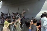 Ľudia bežia okolo amerického transportného lietadla C-17 na medzinárodnom letisku  Hámida Karzaja v Kábule 16. augusta 2021.